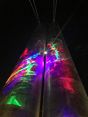 Close up of laser lumia with the moon in the background between the pylons
